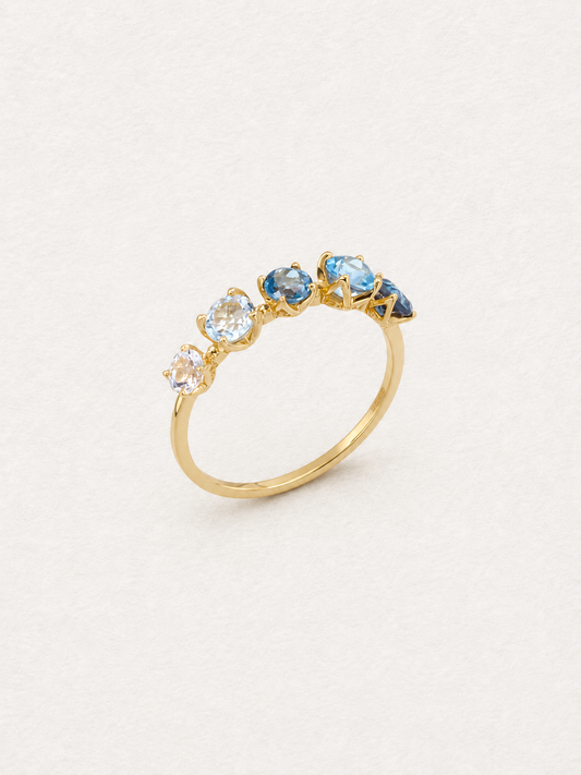 Angled view of the Bonbon ring with five pale-to-deep blue topaz stones on a gold-toned band.