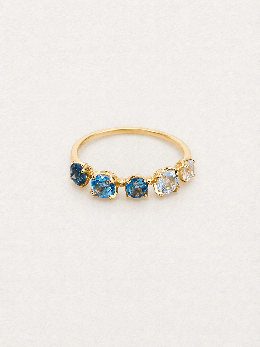 Front view of the Bonbon blue topaz ring showing five faceted stones and a slim gold-toned band.