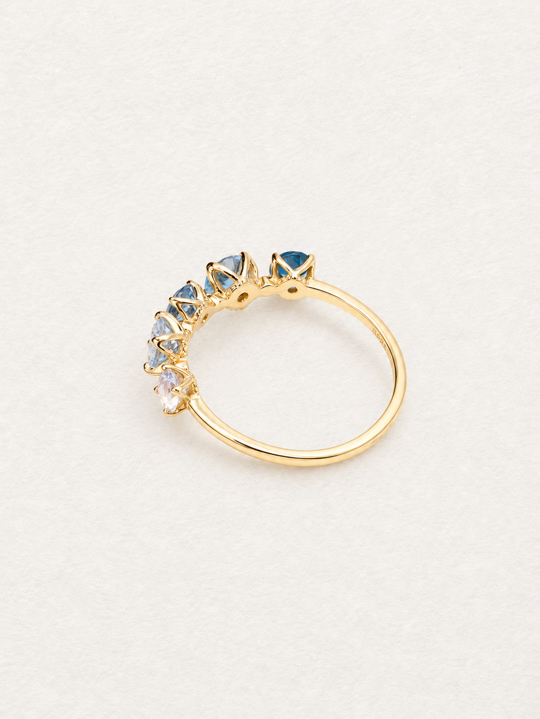 Rear angled view of the Bonbon blue topaz ring showing the open stone settings and gold-toned band.